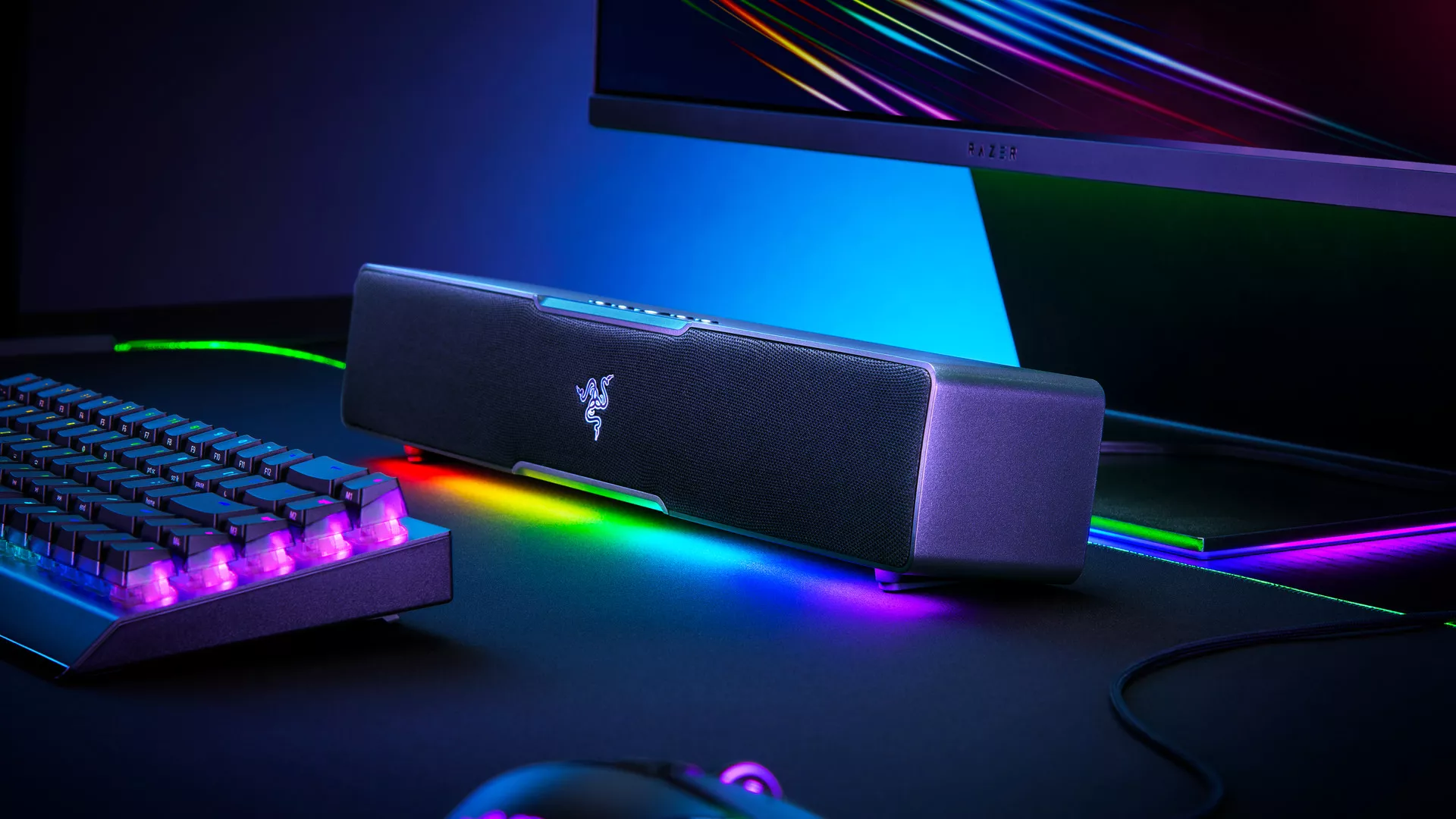 Barre de son Razer Leviathan V2 X posée sous un écran, avec clavier et éclairage RGB dans un setup gaming