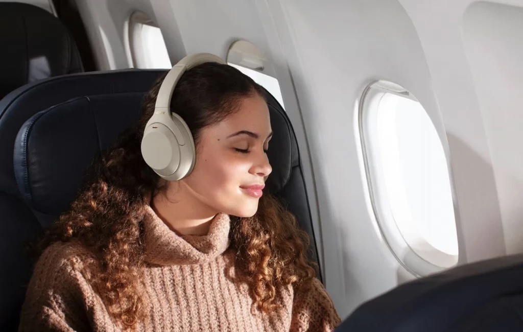 Femme avec un casque Sony à réduction de bruit écoutant de la musique dans un avion